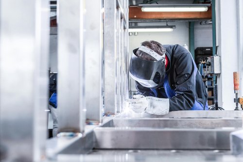 Mann mit Arbeitshose und Schutzbrille am schweißen 