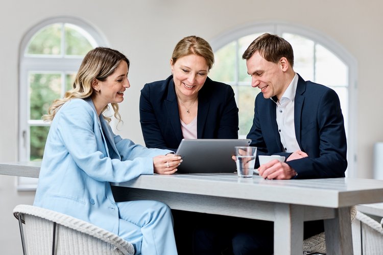 Zwei Frauen und ein Mann am Stehtisch mit Laptop