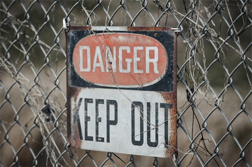 Maschendrahtzaun mit Warnschild DANGER KEEP OUT